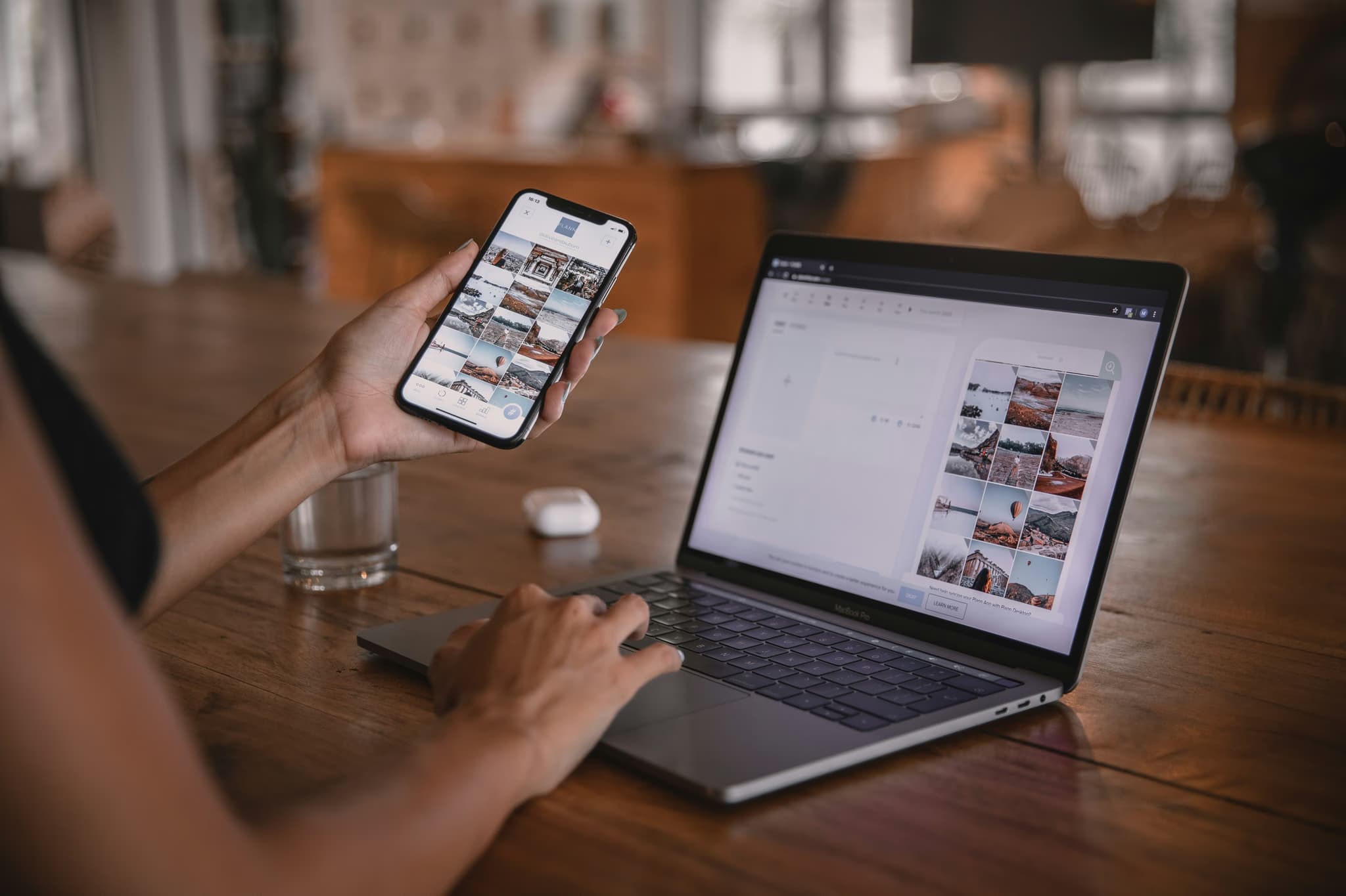 Person holding smartphone with laptop on desk